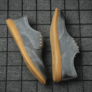 Detailed view of grey suede Brogue shoes with decorative perforations and tan rubber soles
