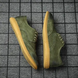 Top-down view of men's green suede brogue shoes on a black metal grid background