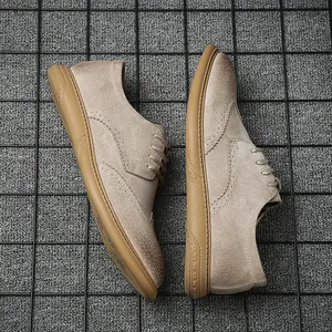 Macro detail view of men's sand-colored suede brogue shoes on a dark grid background