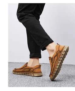 Detailed view of men's brown slip-on loafers featuring decorative handmade stitching detail