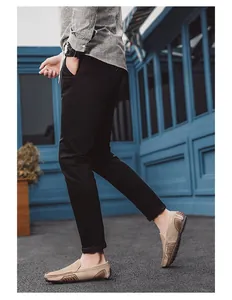 Vista lateral de mocasines de cuero beige con pantalones negros en entorno urbano