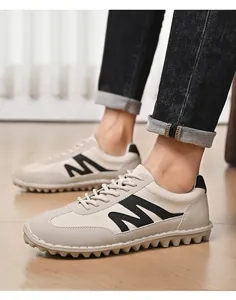 Detaillierte Nahaufnahme von Herren-Retro-Sneakern mit M-Logo-Detail auf Holzboden