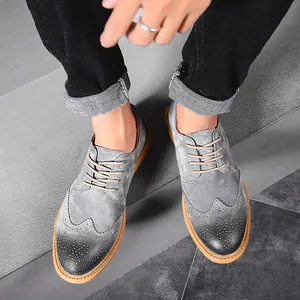 Close-up of stylish gray suede men's wingtip brogue shoes in casual business setting
