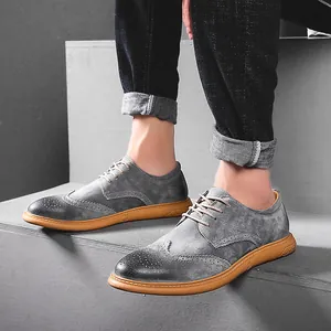 Close-up detail of grey leather Brogue shoes with tan soles on minimalist grey steps