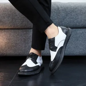 Close-up detail of stylish black and white brogue leather shoes worn with black trousers