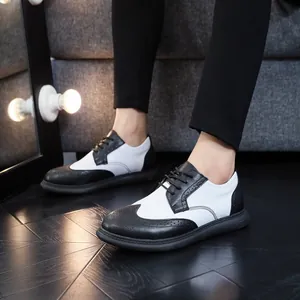 Detail view of men's black and white wingtip brogue leather shoes worn by a model