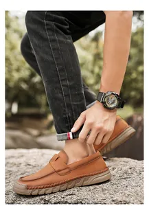 Side view of men's retro brown leather loafers worn with casual black jeans outdoors.