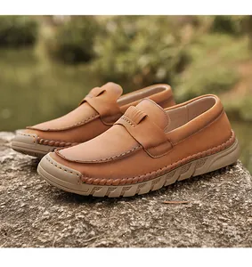 Detailed side view of brown leather casual loafers on a natural stone surface.