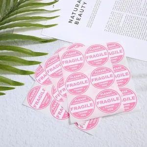Primer plano de pegatinas de envío Fragile rosas con texto Handle with Love en fondo blanco
