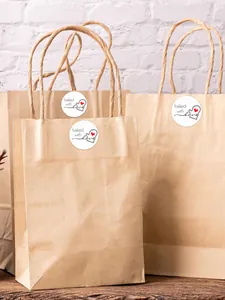 Detailed view of baked with love round stickers applied to kraft paper gift bags