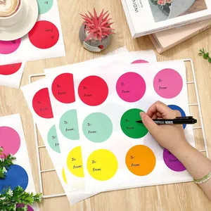 Dettaglio che mostra una persona che scrive su etichette regalo colorate circolari fai da te