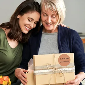 Dettaglio di un'etichetta regalo tonda nude su una scatola kraft tenuta da due donne.