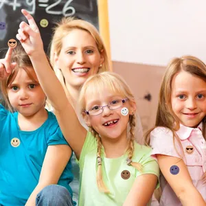 Cheerful children in a classroom wearing small colorful smiley face reward stickers