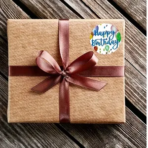 Macro view of Happy Birthday sticker with balloons on a brown kraft gift box with ribbon