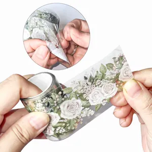 Detailansicht von elegantem Rosen-PET-Band, das den Abziehvorgang für Scrapbooking zeigt.