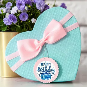 Decorative round Happy Birthday sticker with pink scalloped edge on a blue gift box