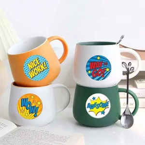 Detail showing colorful reward stickers with English motivational phrases on mugs