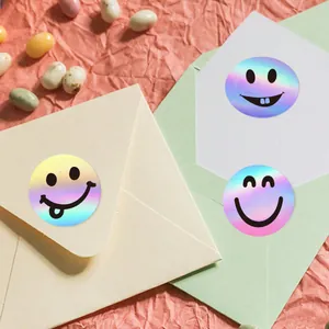 Decorative holographic smiley face stickers on cream and green envelopes for gifts.