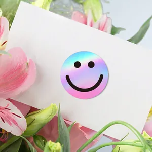 Macro view of a vibrant holographic smiley face sticker placed on a white gift card.