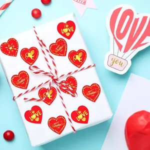 Vista dettagliata di adesivi a cuore rosso dorati su una scatola regalo bianca per San Valentino.