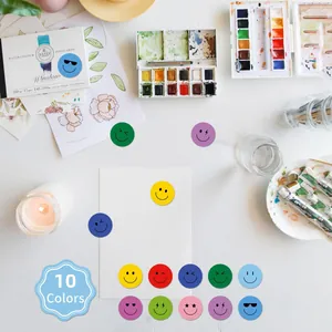Macro view of colorful smiley face stickers arranged on a white craft desk with watercolor props.
