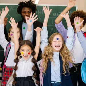 Happy children and teacher wearing colorful smiley face reward stickers in a classroom.