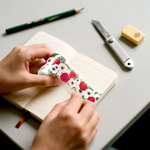 Detailed view of applying rose floral PET tape to a journal page with art supplies.