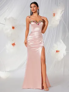 Detailed view of luxury pink satin evening gown with floral embroidery and high slit.