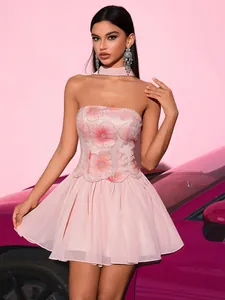 Dettaglio di un abito da festa rosa con scollo all'americana, ricami floreali e strass
