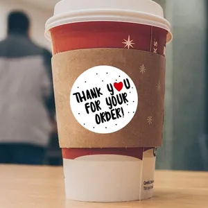 Close-up of a circular 'Thank You For Your Order' sticker on a coffee cup sleeve.