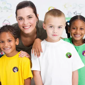 Close-up of happy children wearing colorful teacher reward stickers in a classroom