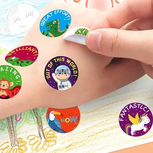 Close-up of colorful cartoon reward stickers with English praise phrases on a hand