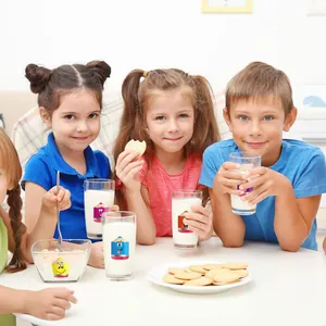 Autocollants en forme de crayon sur des verres de lait dans un cadre enfantin.