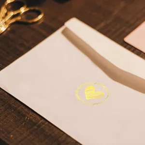 Close-up detail of a decorative golden heart-shaped sticker sealing a white envelope.