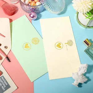 Detailed view of gold foil heart seal stickers on pastel green and cream envelopes