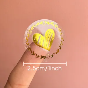 Close-up detail of a 1-inch transparent gold foil heart sticker for envelope sealing