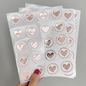 Detailed view of rose gold heart-shaped envelope seal stickers on transparent sheets