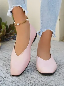 Close-up view of elegant pink square toe flats worn with a stylish pearl anklet.
