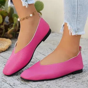 Detailed macro view of vibrant pink pebbled leather flat shoes with a chic V-cut design