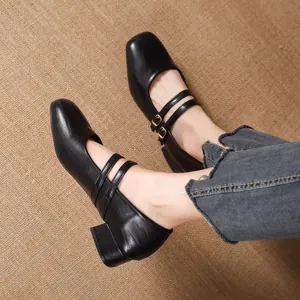 Chaussures Mary Jane noires classiques avec bout carré et doubles brides sur fond rustique.