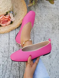 Close-up of bright pink faux leather flat shoes with white trim and textured finish