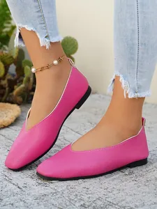 Detailed view of vibrant pink pebbled faux leather flat shoes worn with blue jeans
