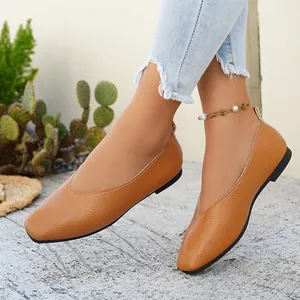 Close-up of women's tan pebbled leather flat loafers with retro minimalist design.