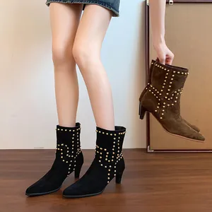 Botines de ante con punta afilada y remaches dorados con tacones de aguja.