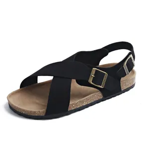 Nahaufnahme von schwarzen Sandalen mit Kreuzriemen, Kork-Fußbett und Metallschnalle