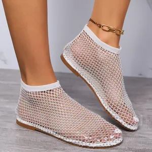 Dettaglio dei sandali piatti in rete bianca decorati con strass scintillanti.