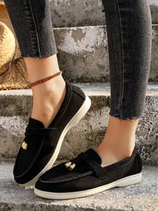 Close-up of black suede slip-on loafers with decorative gold hardware on stone steps