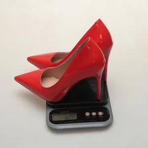 Detail view of a red pointed-toe stiletto pump on a scale showing its light weight