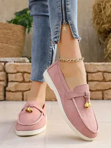 Detail view of pink suede slip-on loafers featuring decorative gold tassels for women.