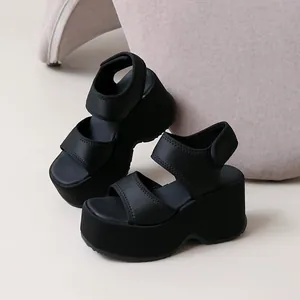 Vue détaillée de sandales compensées noires avec semelle plateforme et larges brides.